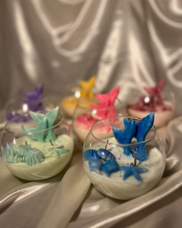 شموع معطرة داخل أكواب زجاجية مزينة بذيل حورية البحر وأشكال بحرية بألوان متعددة.