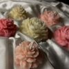 توزيعات شموع بتصميم وردة وردية داخل علبة شفافة مربوطة بشريط وردي وبطاقة تحمل كلمة "Rose".